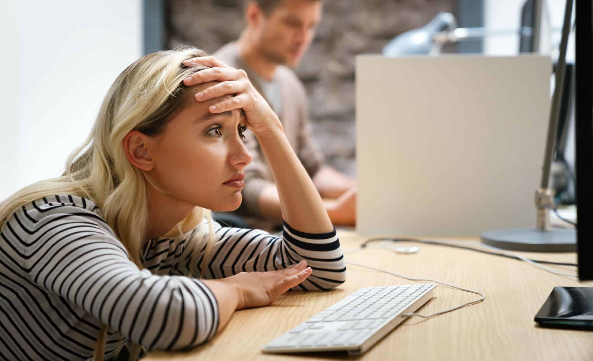 Portrait of a disappointed woman programmer looking stressed out while working on a computer code